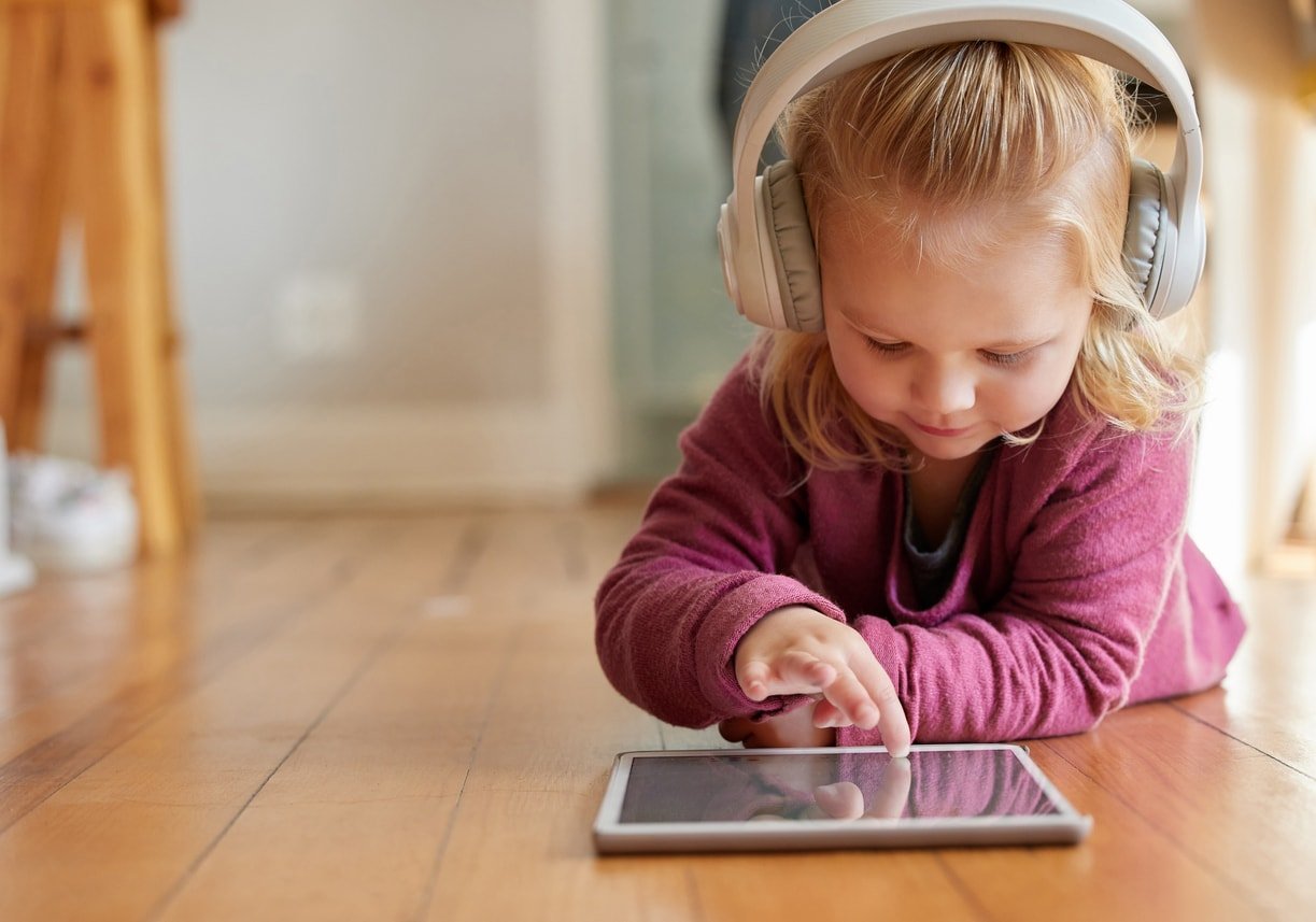 Shot of an adorable little girl wearing headphones whiles using a digital tablet