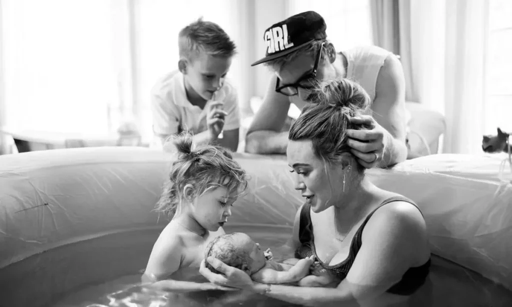 Hilary Duff in a birthing poll holding her newborn and showing her family after giving birth.