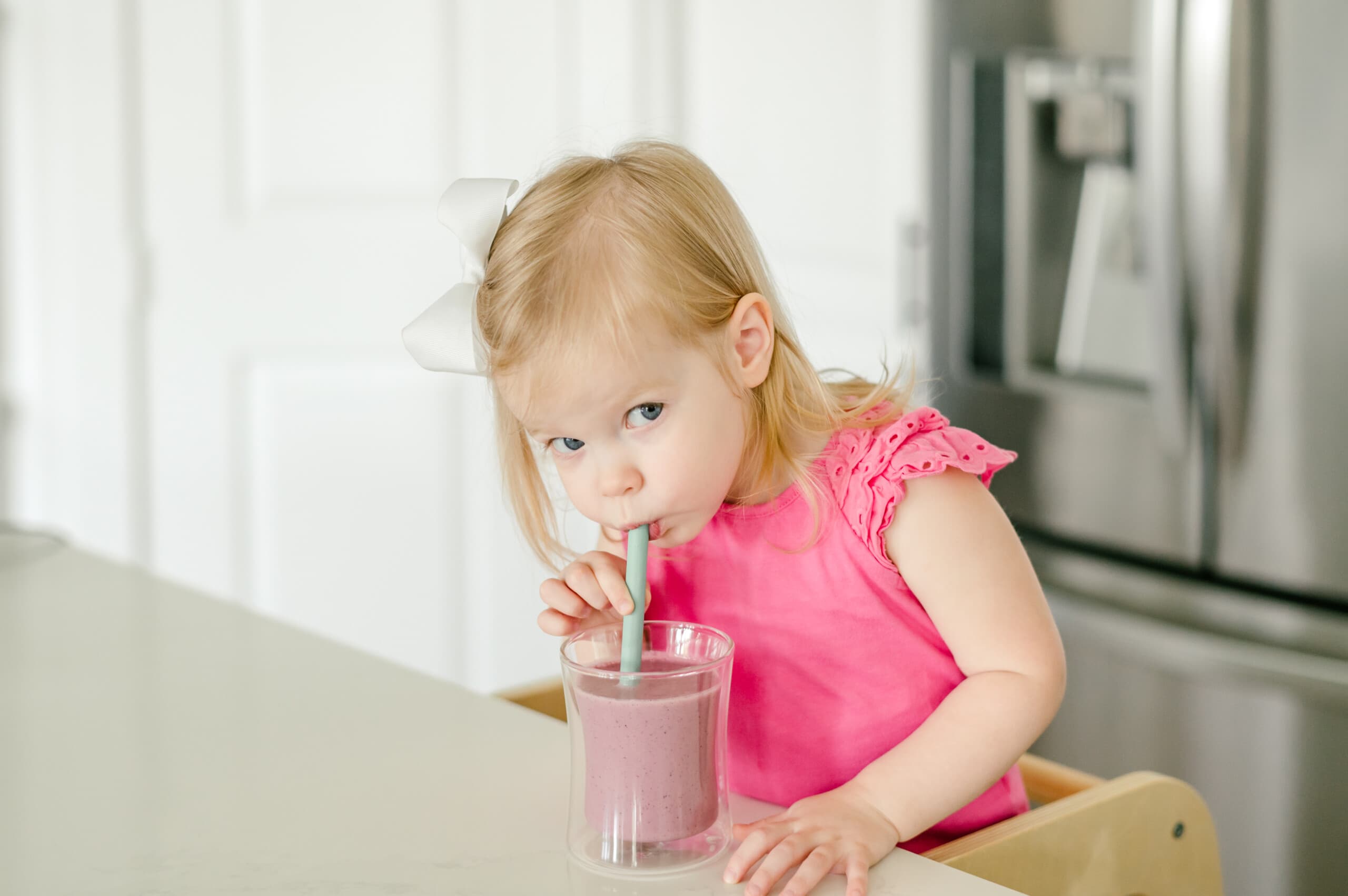 Little girl drinking a smoothie in the kitchen