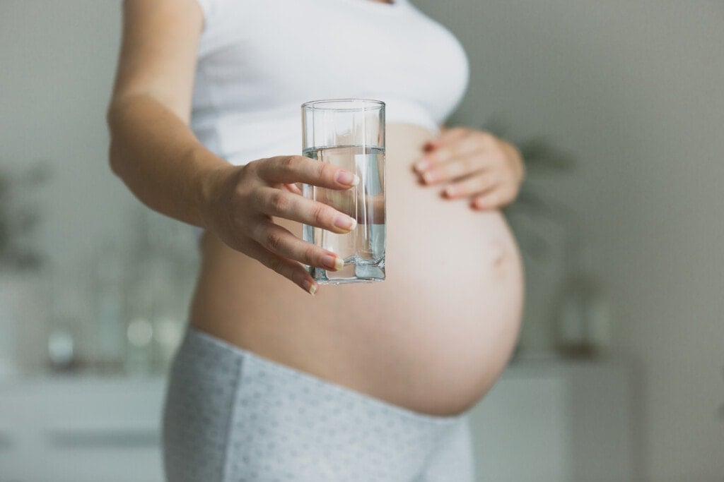 Closeup photo of pregnant woman holding glass of water