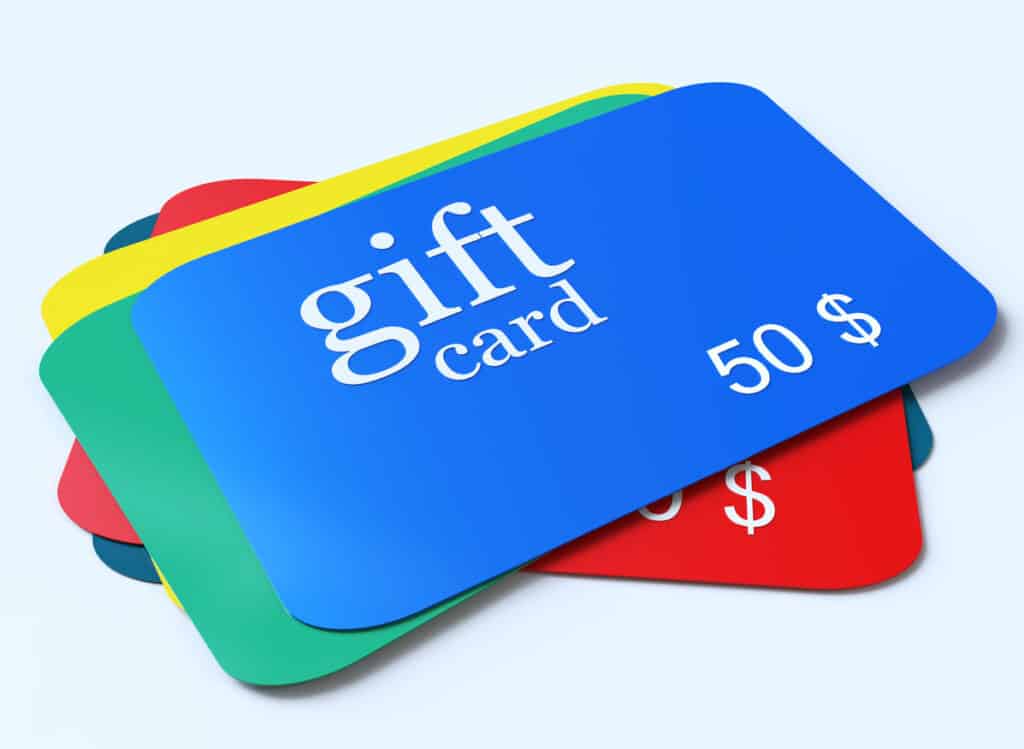 A stack of colorful gift cards is displayed, perfect for must-have baby products. The top card is blue with the text gift card and 50 $ on it, while other cards in red, yellow, and green are partially visible underneath.