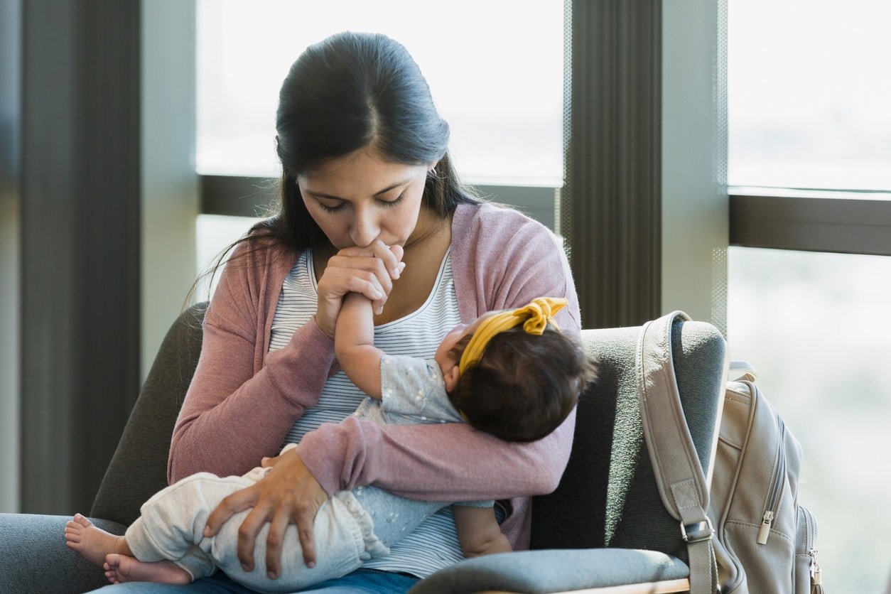 As she waits in the psychiatrist's office, the new mom closes her eyes as she kisses her baby's hand.