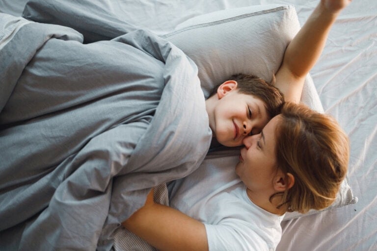 A young mother and her 7-year-old son are having a cuddle time in bed.