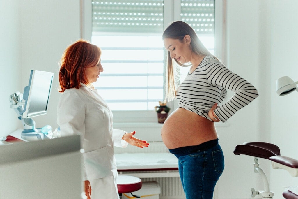 Female doctor talking with a pregnant young woman and explaining her a medical procedure.