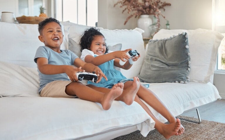 Shot of a brother and sister playing video games on the sofa at home