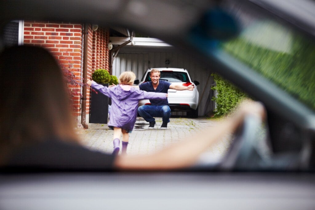 Little girl running to her dad while her mom is in the car driving off. Divorced parents concept.