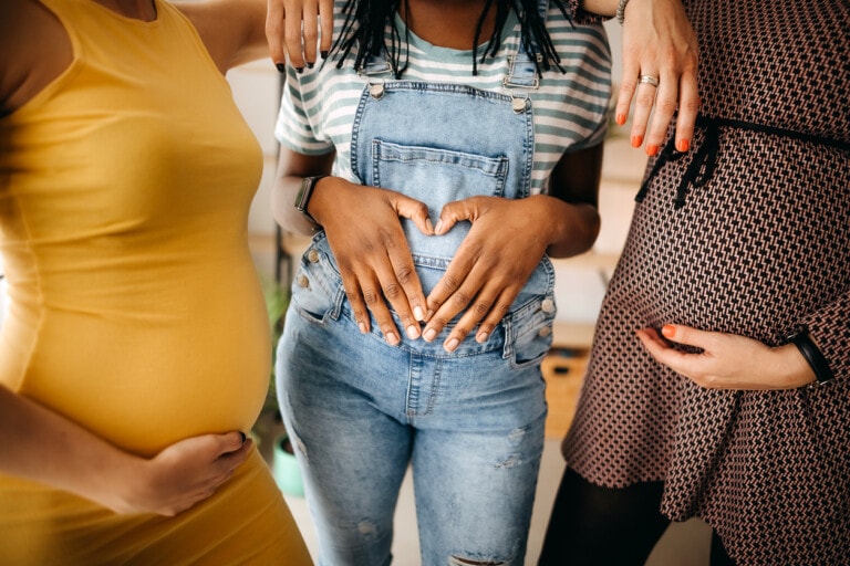 Portrait of three young pregnant women holding their bellies
