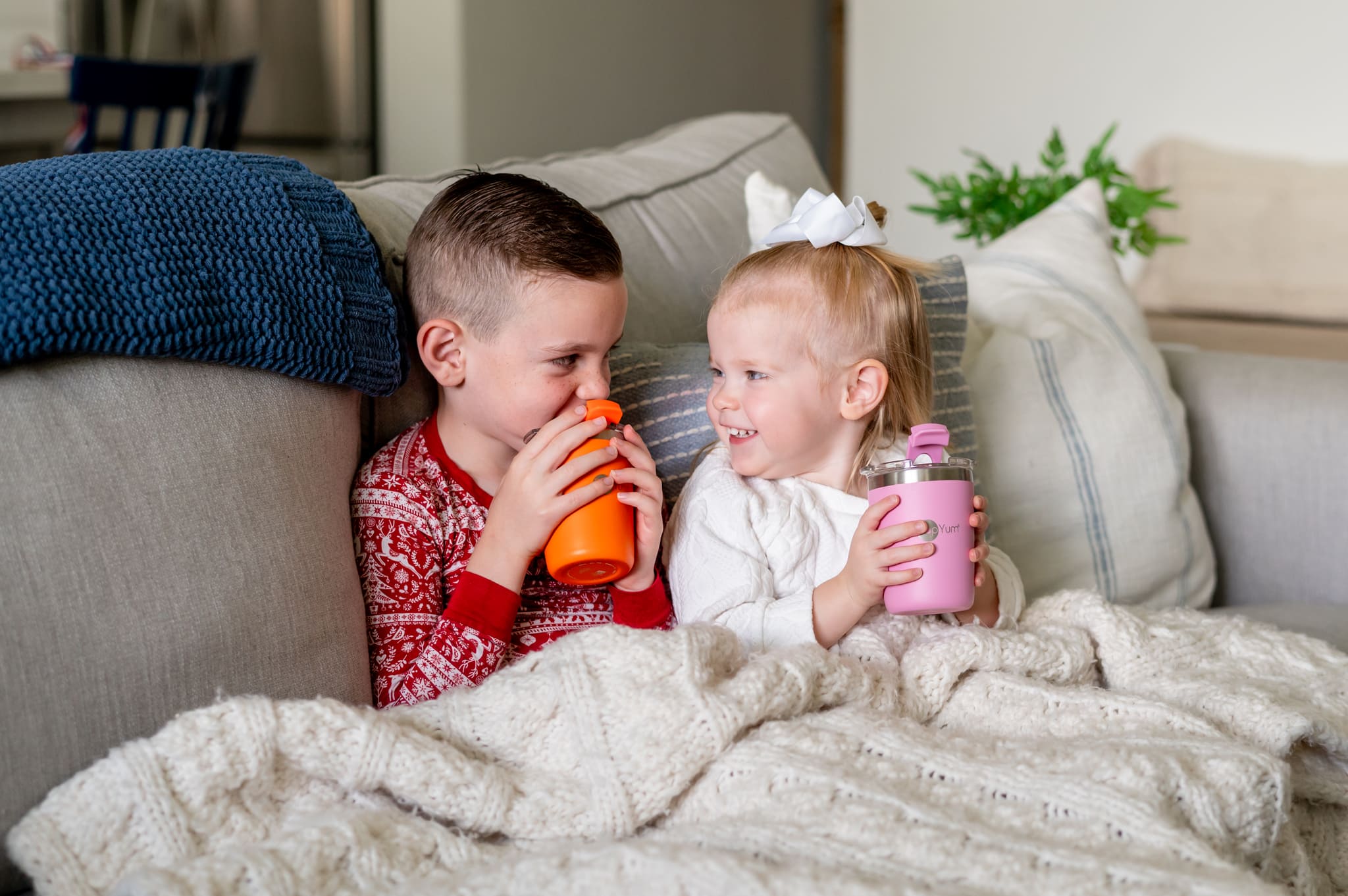 Kids sitting on the couch with a blanket and drinking from their PopYum kids cups