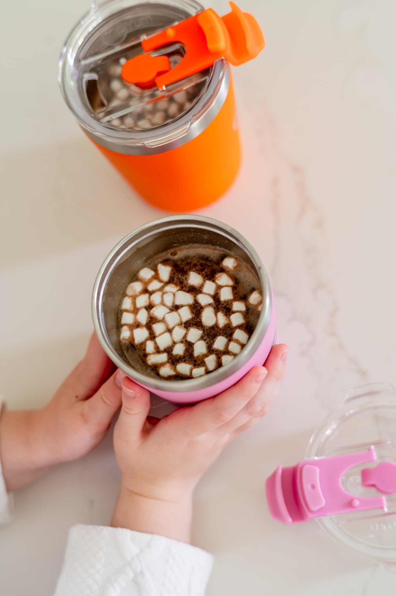 Two insulated kid cups filled with hot cocoa and marshmallows