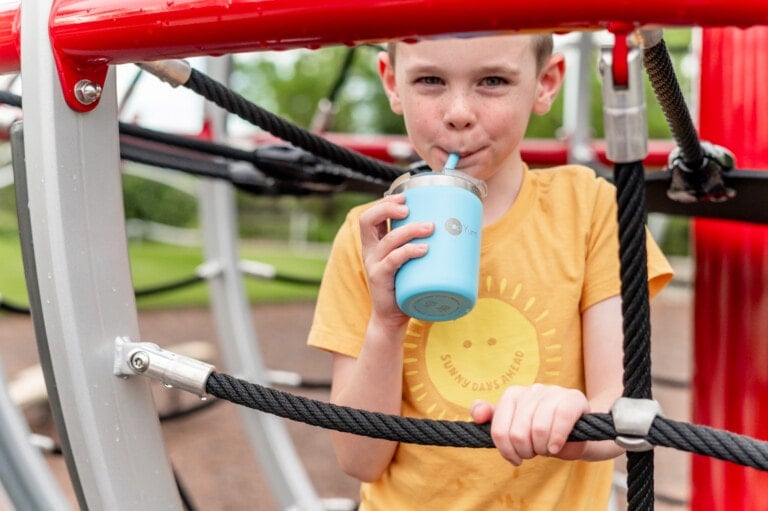 Young boy on the playground drinking from his blue PopYum insulated Kids' Cup
