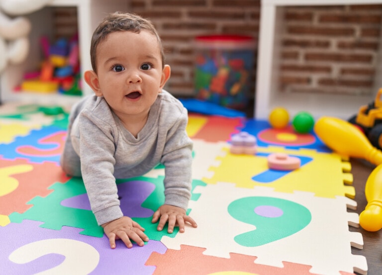 Adorable hispanic baby crawling on floor at daycare