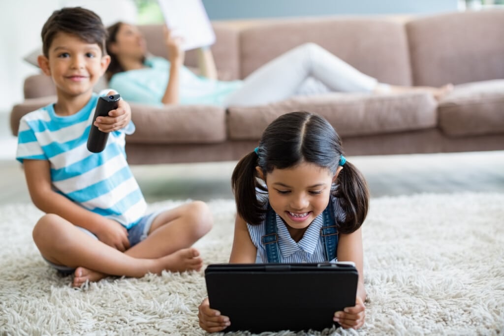 Boy watching television and girl using digital tablet in living room at home