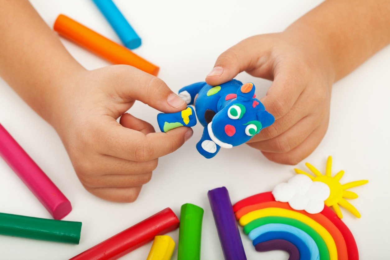 Child playing with colorful clay making animal figures - closeup on hands