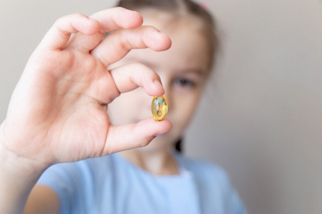 Close up child holding in hand with omega 3 vitamin, fish oil