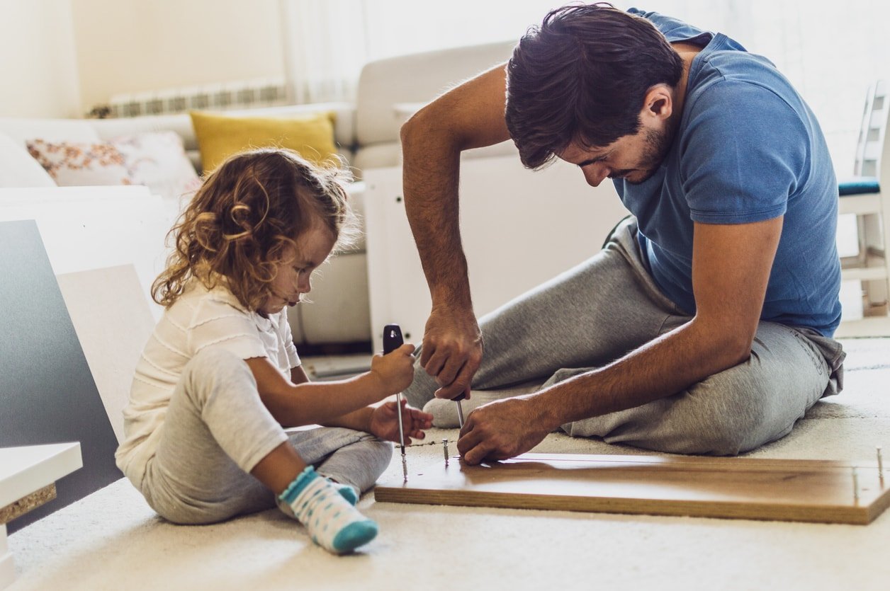 A girl is helping her father to make some furniture. DIY work.
