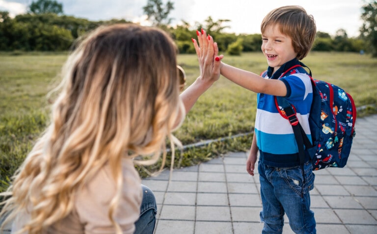 Cute boy goes to school and gives his mom a high-five