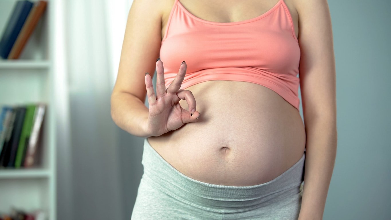 Pregnant lady showing ok sign, prenatal care, healthy baby in third trimester