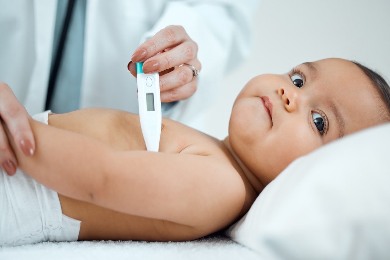 Shot of a paediatrician taking a baby's temperature with a thermometer under the armpit in a clinic