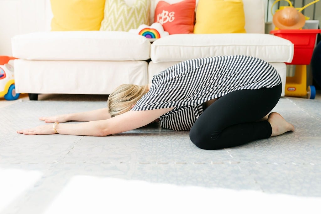 Woman doing a Wide-Legged Child's Pose on the playroom floor