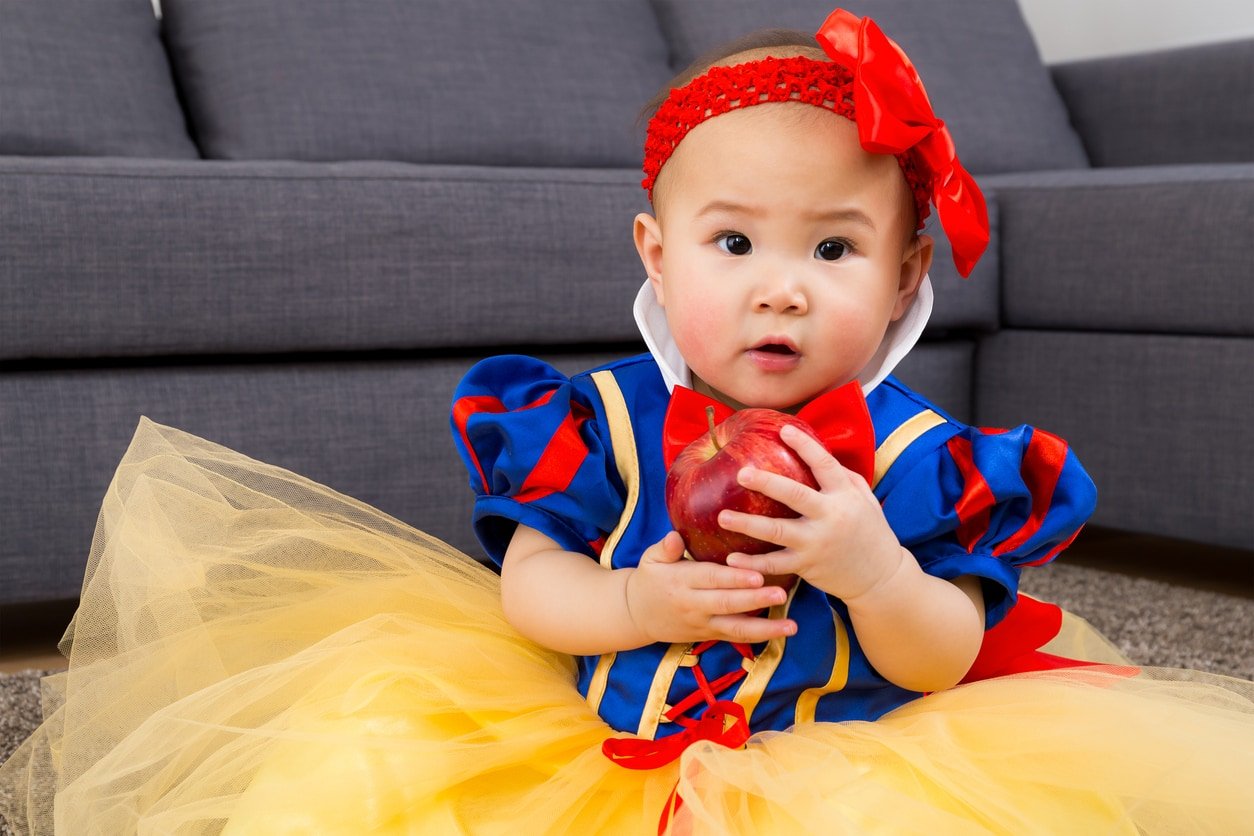 Baby girl holding an apple dressed in Snow White costume