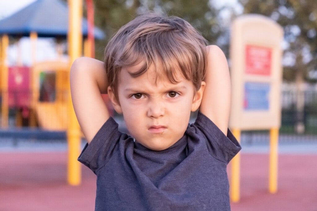 Caucasian Little child boy looking at the camera posing at a playground looking grumpy or has an attitude
