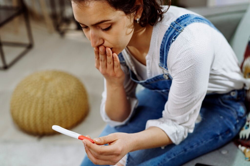 Worried woman holding pregnancy test.