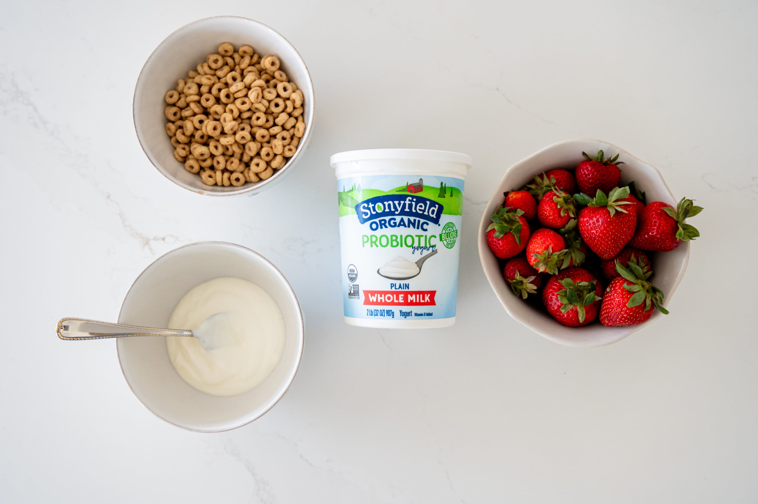 Stonyfield yogurt with bowls of yogurt, cheerios, and strawberries