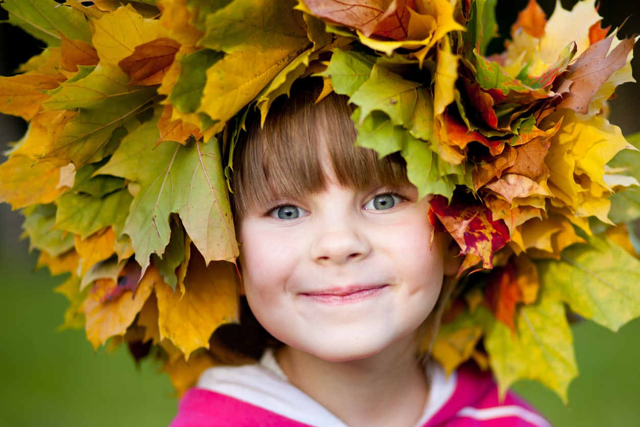 Colorful picture of little girl wearing a leaf crown made with autumn leaves. Focus on the eyes.