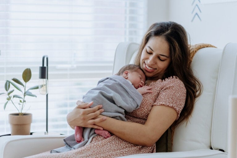 Mother holding her baby boy sitting in a glider in the nursery room