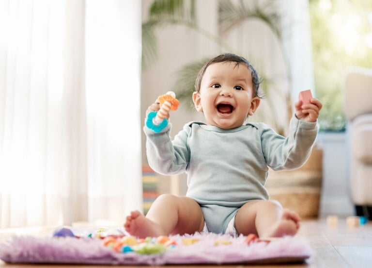 Shot of an adorable baby boy sitting up on a mat playing with toys at home