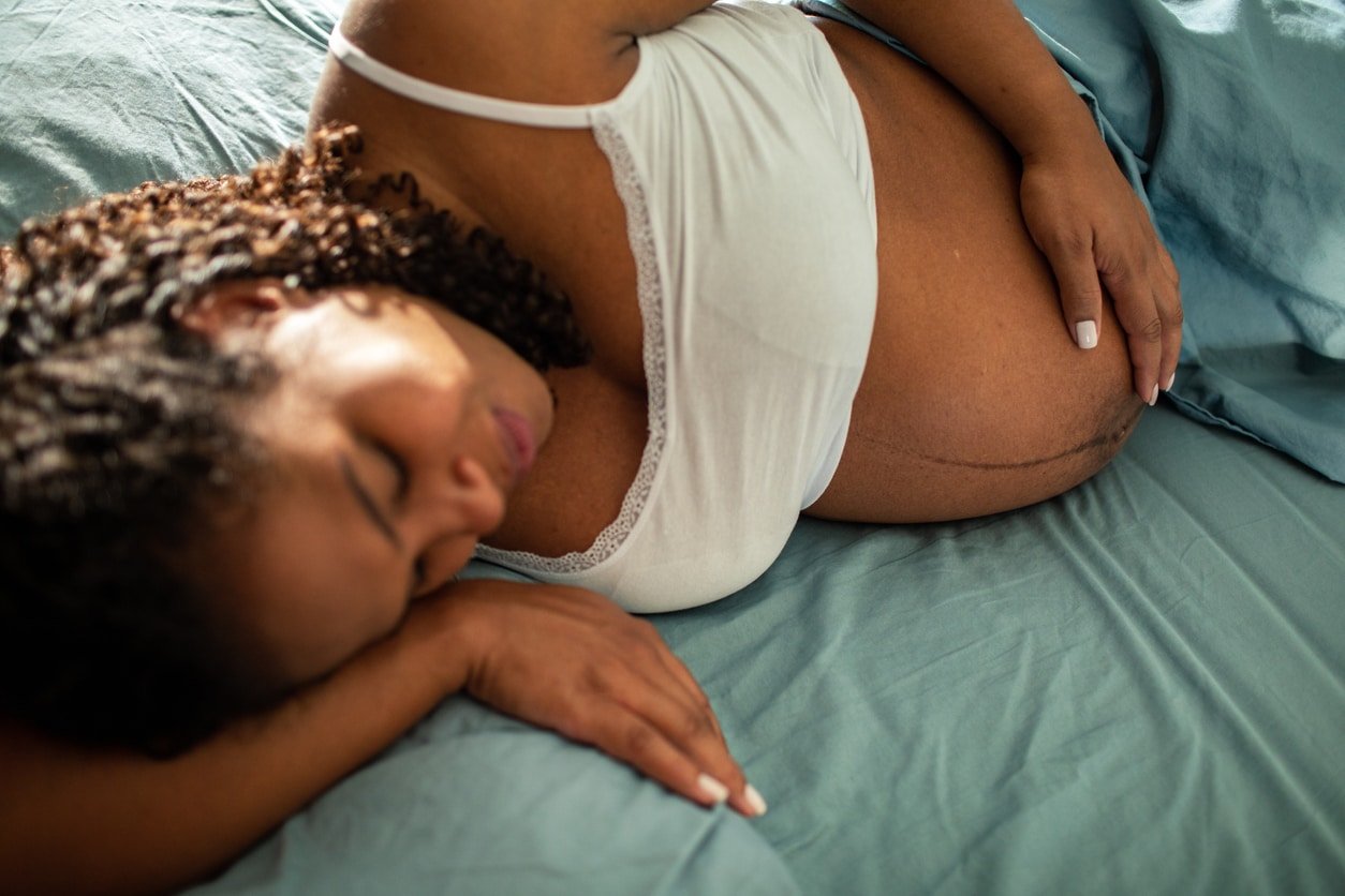 Close up of a Young pregnant woman waking up in the morning in a bedroom