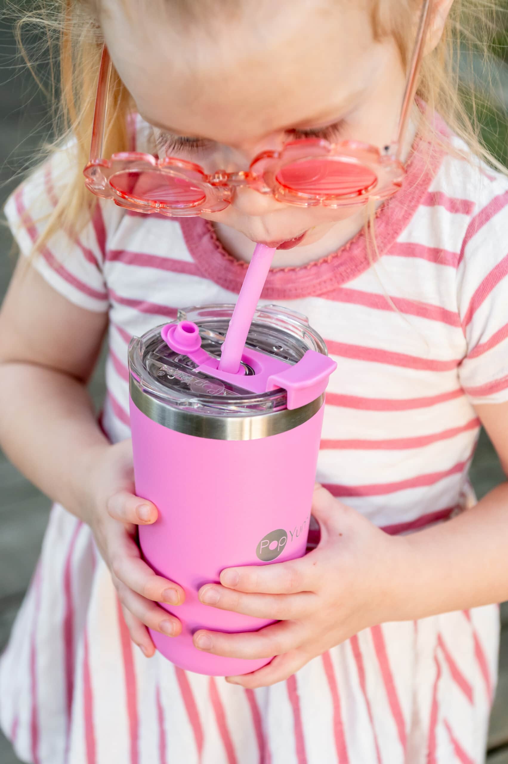 Little girl drinking out of her pink PopYum 13 oz kid cup through the straw