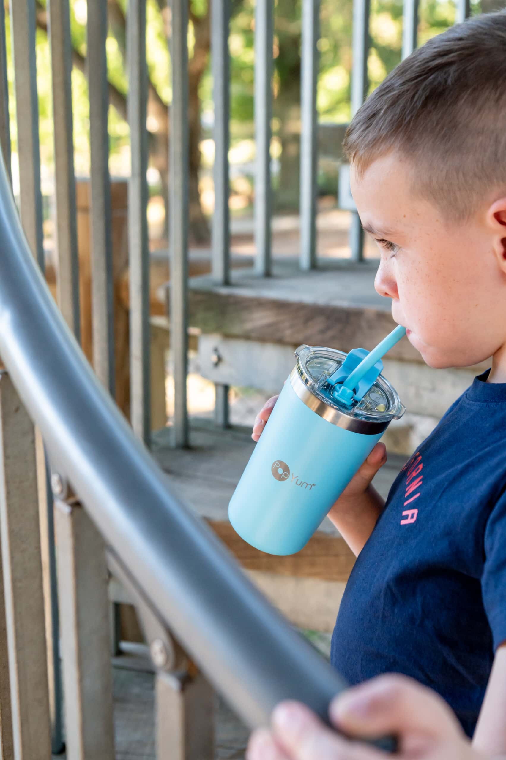 Young boy drinking from his blue PopYum 13oz kid cup outside