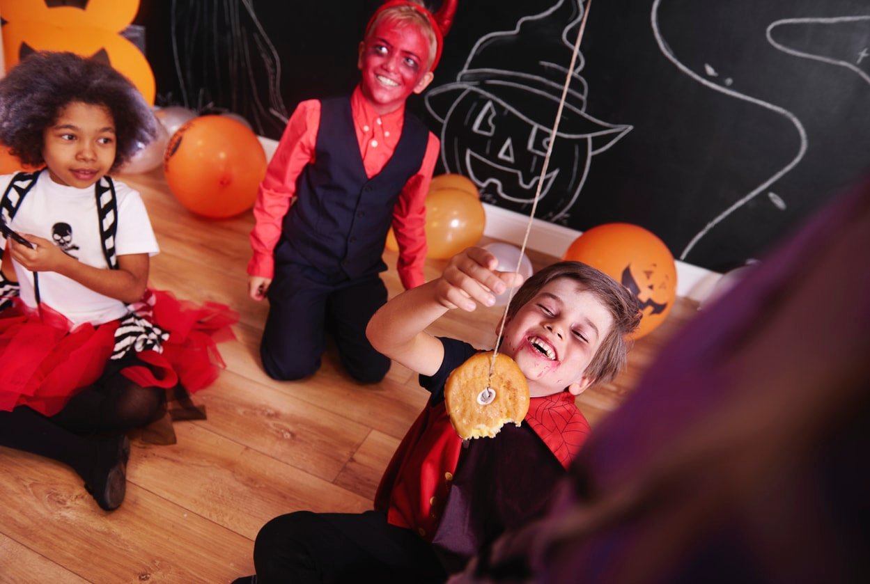 Boy trying to eat doughnuts on a string at a halloween party