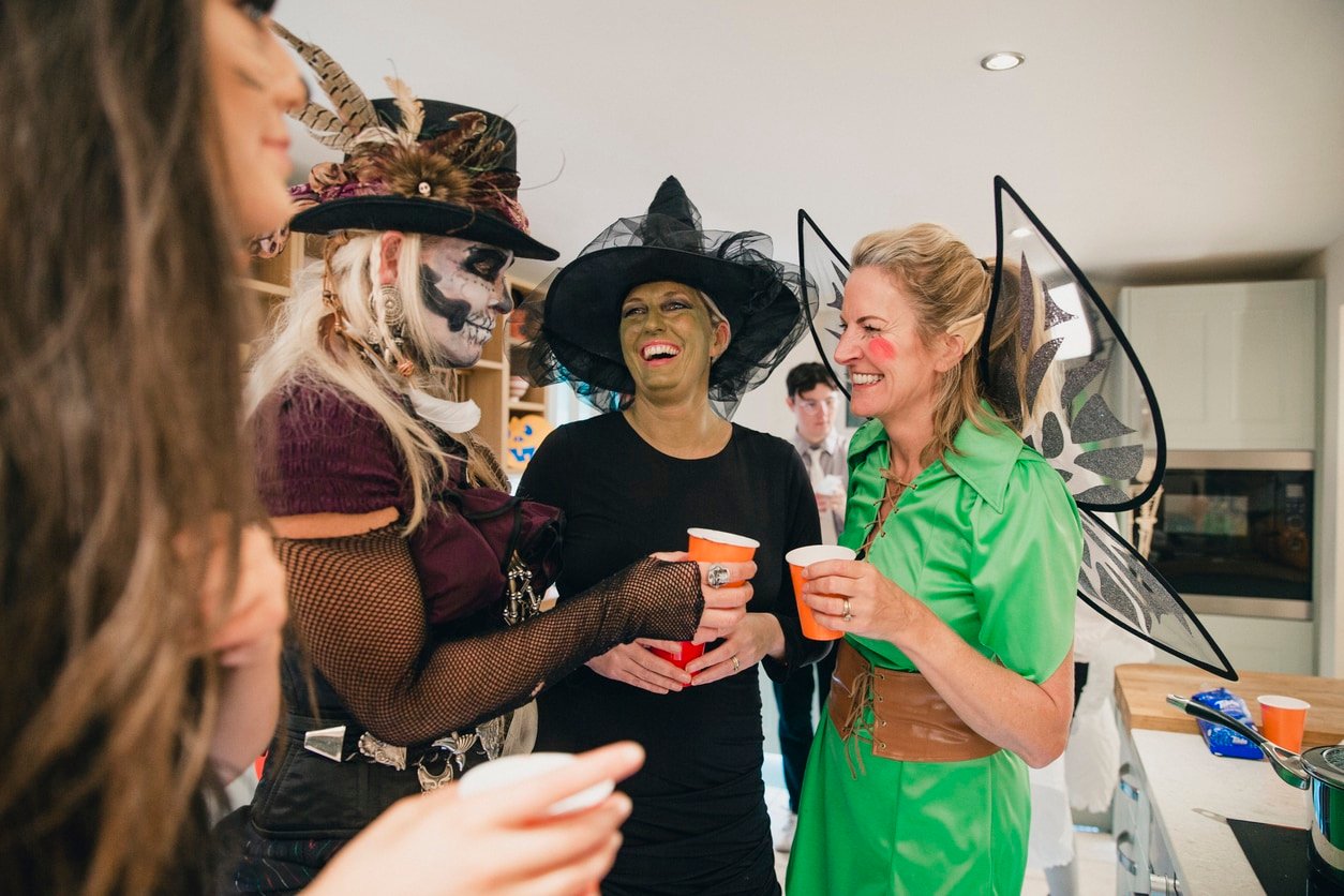 Group of women friends dressed up and laughing at a Halloween party.