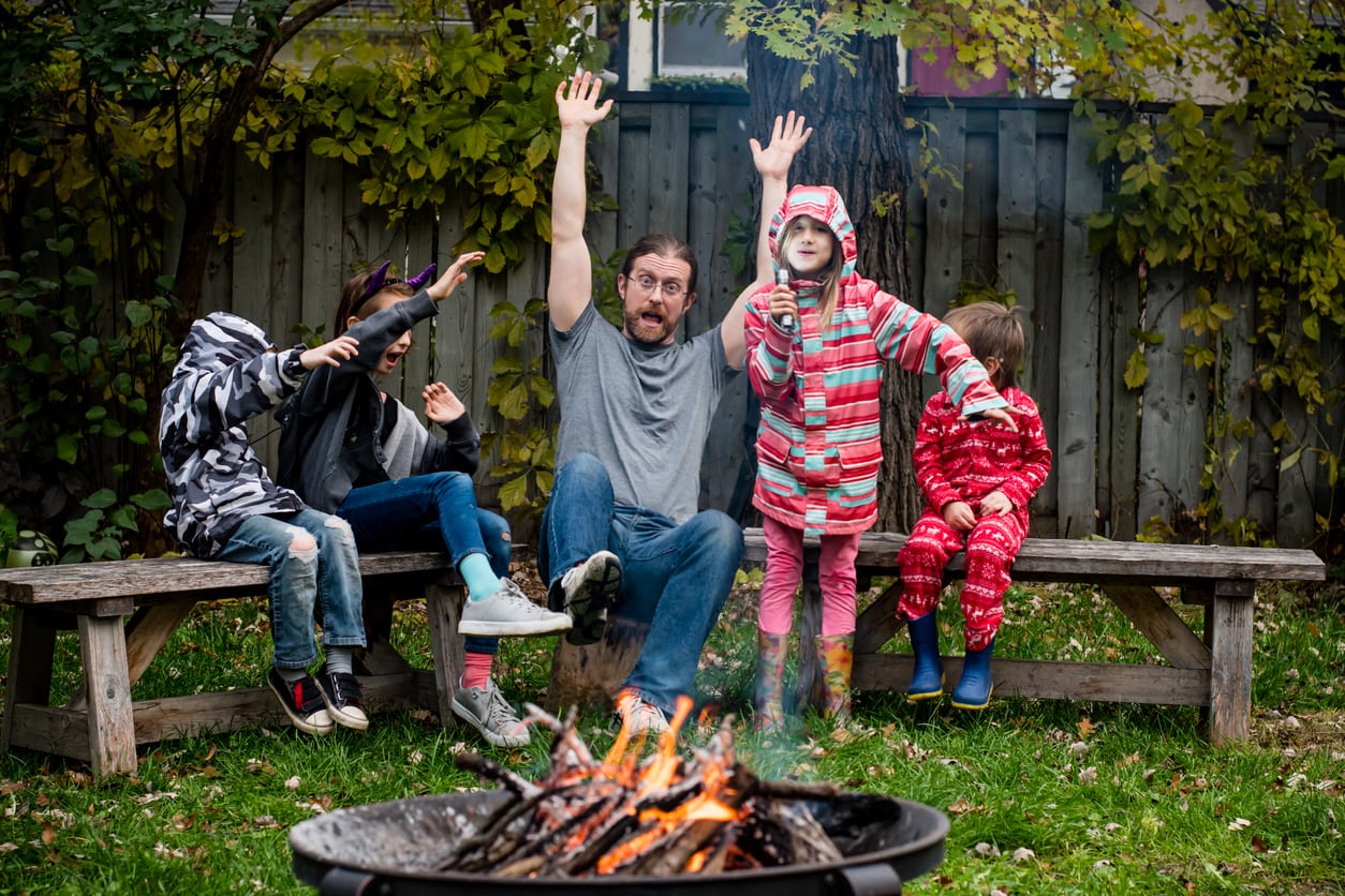 This father with his kids are having a scary and exciting time telling stories around the fire in a staycation.