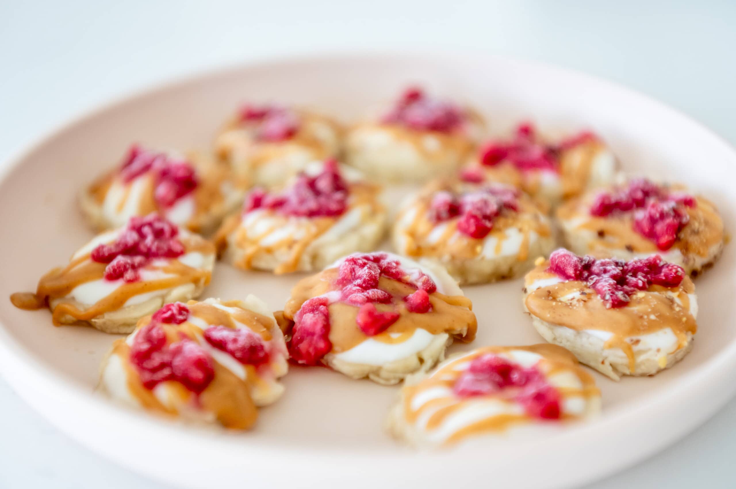 Close up angled view of a pink kids plate with pressed banana yogurt bites.