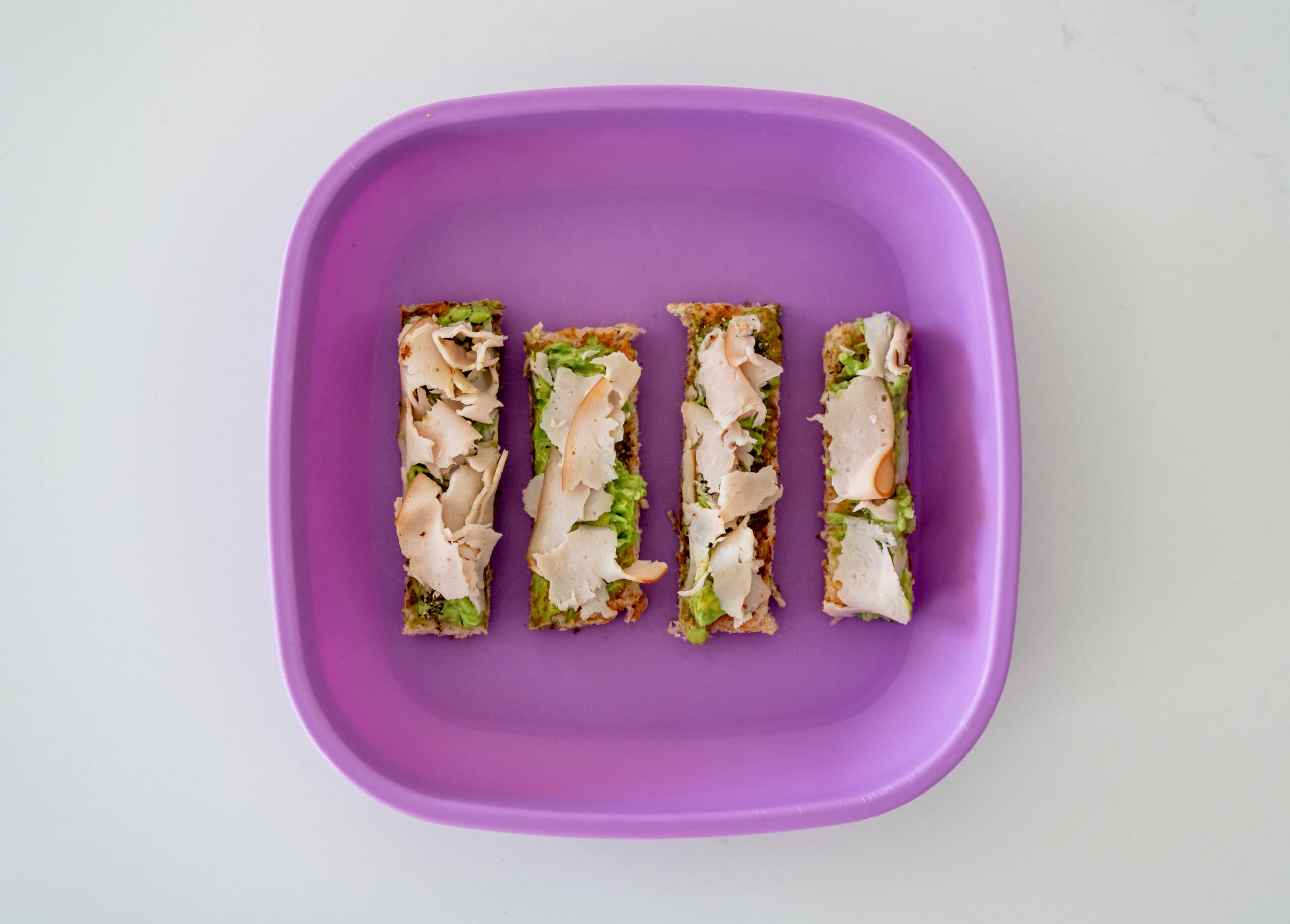 Avocado turkey toast on purple kids plate