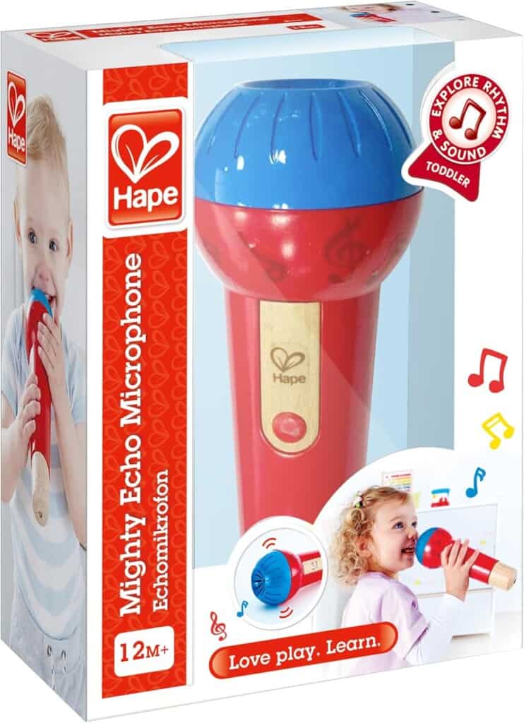 Box of Hape Mighty Echo Microphone featuring a child on the left holding the toy, ideal for toddler boy toys. The box displays 12M+ and includes a circular logo saying Explore Rhythm & Sound. The microphone is red with a blue top and wooden handle.