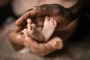 A beautiful view of interracial family holding baby feet in hands, mixed by black and white skin color