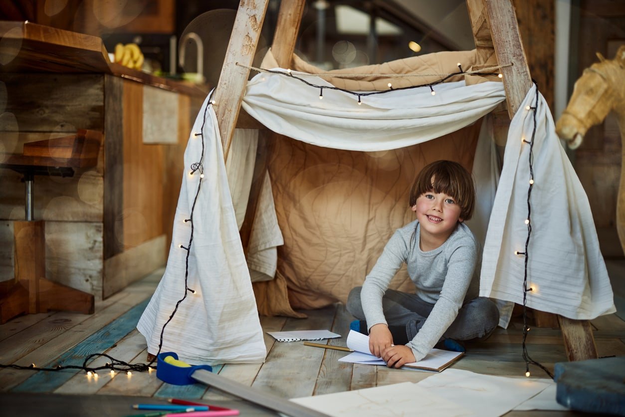 Happy little boy enjoying in his creative time at home building a fort.
