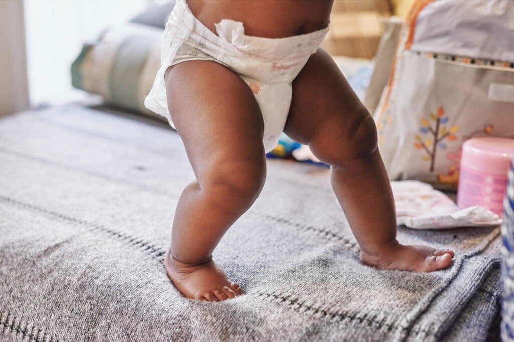 Cropped shot of a baby learning to walk on the bed at home