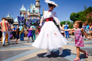 Mary Poppins smiles at a young child as she leads a line of children in song and dance in front of Cinderella's castle during Disney's 60th Diamond Celebration.