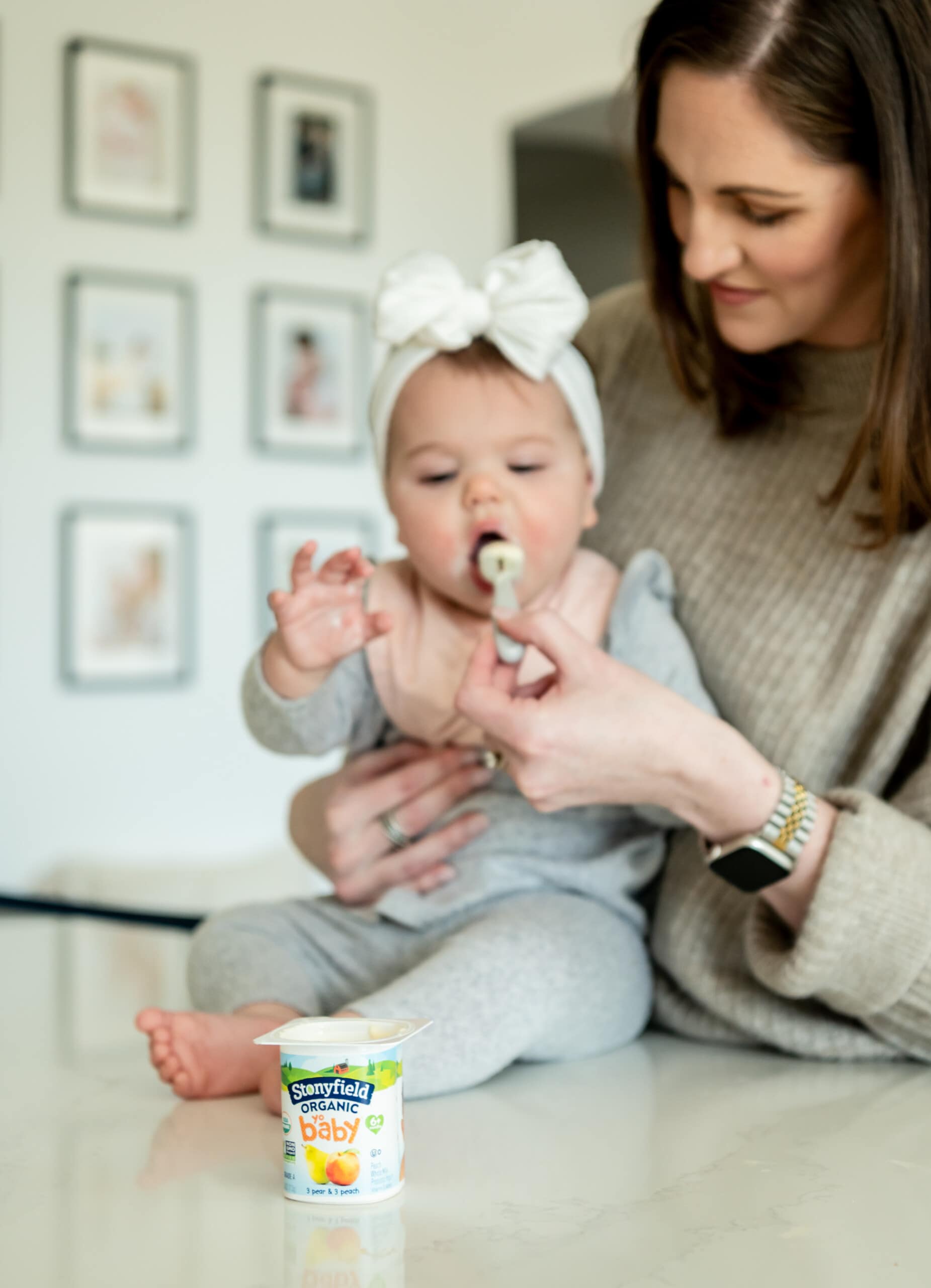 Baby eating yogurt on counter with her mom