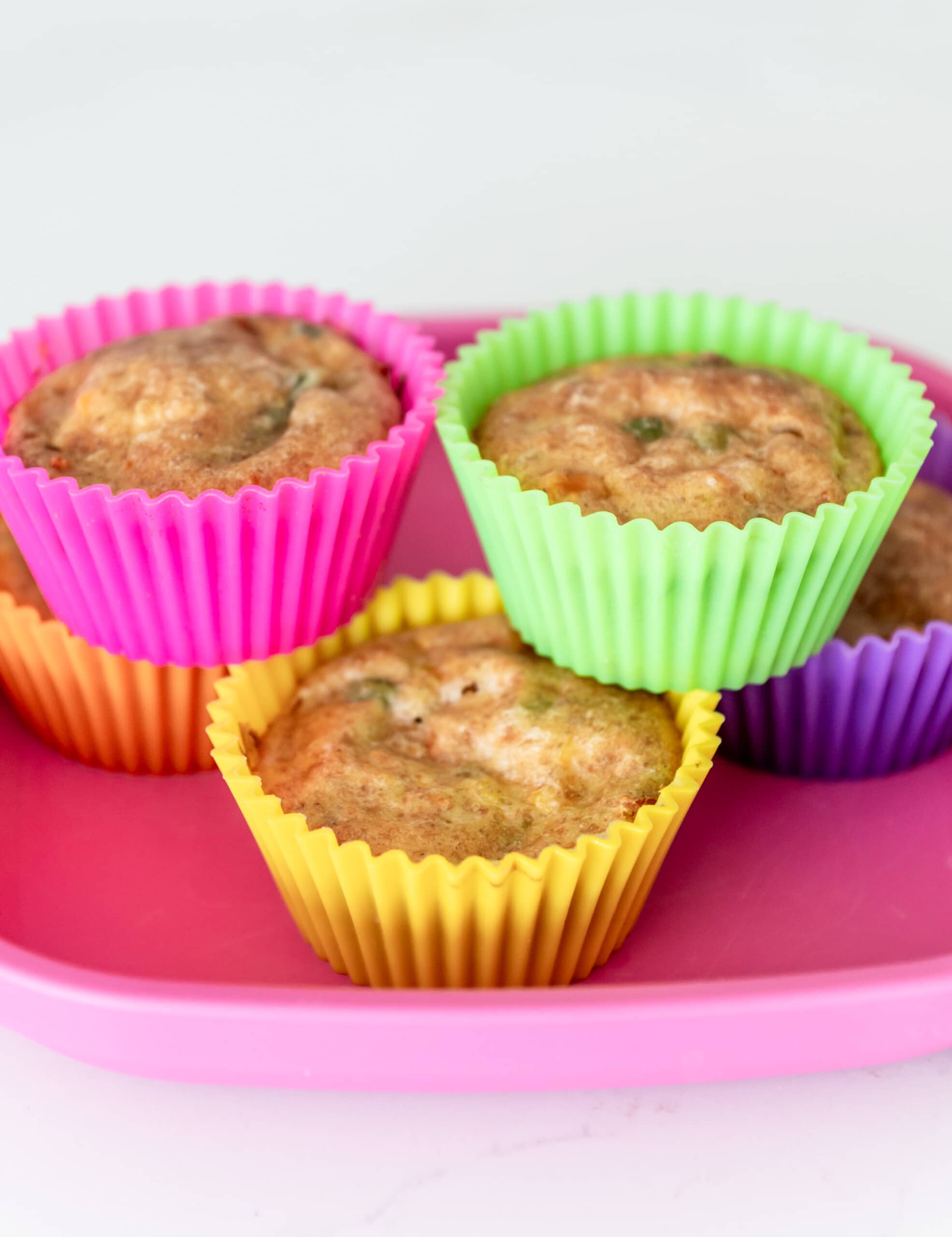 Yogurt veggies bites in silicone muffin tins on a pink kid's plate