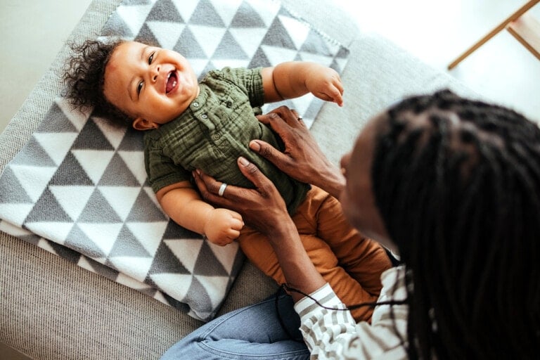 Cute baby boy laughing while mother tickling him