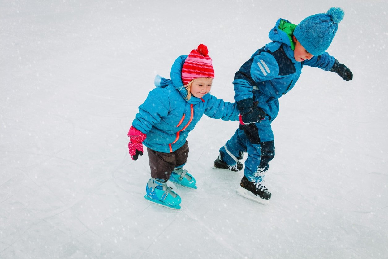 little boy and girl ice skating together in winter snow, kids winter sport