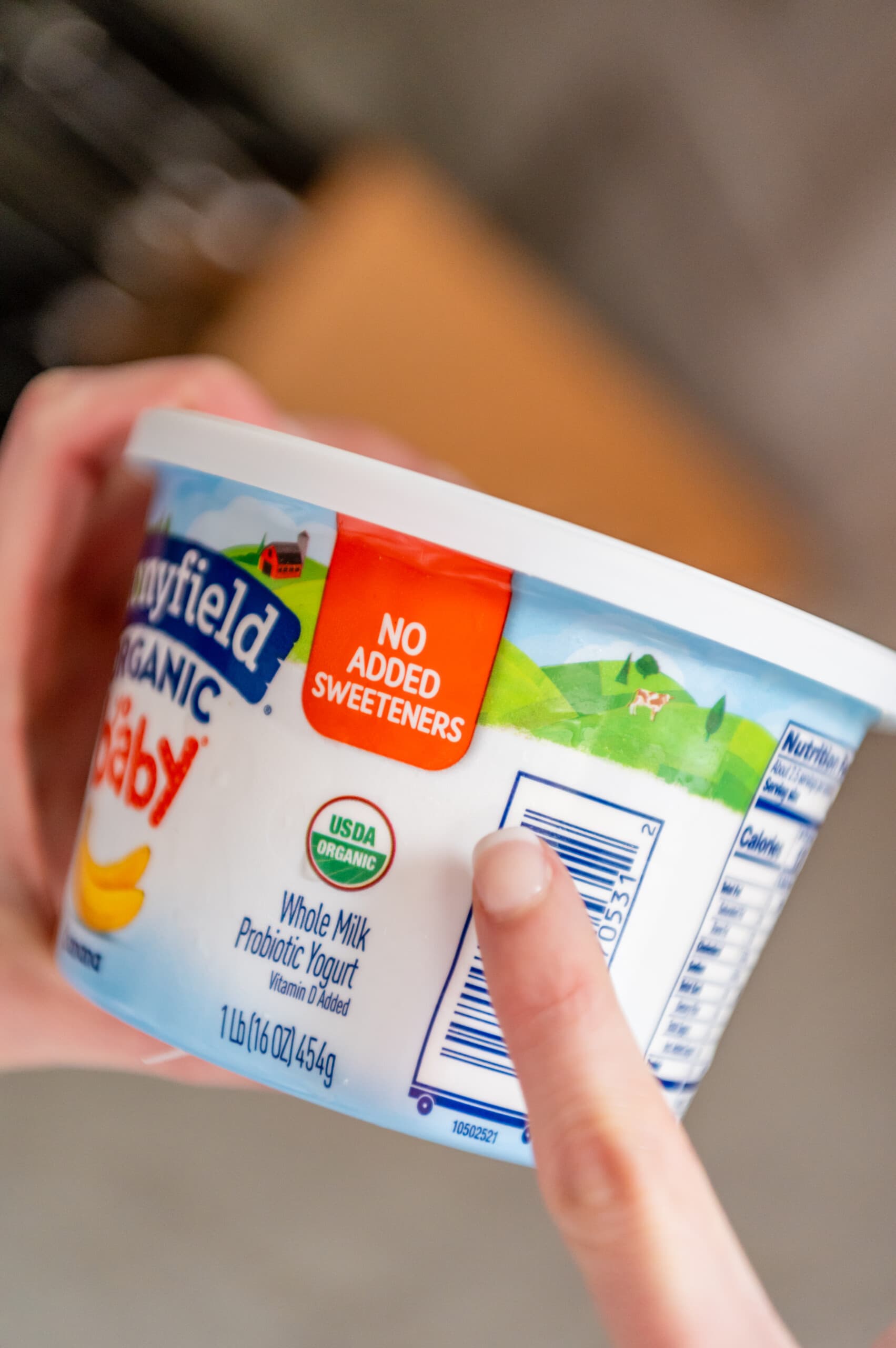 A manicured finger pointing at the no added sweetener sign on the new Stonyfield Yobaby yogurt packaging