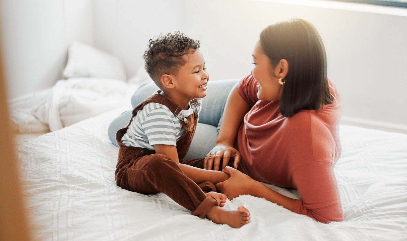 Childcare, love and caring mother playing with toddler son in bedroom, teaching him to talk in a bed room at home. Single parent or mom showing love, affection and care for baby boy, bonding together