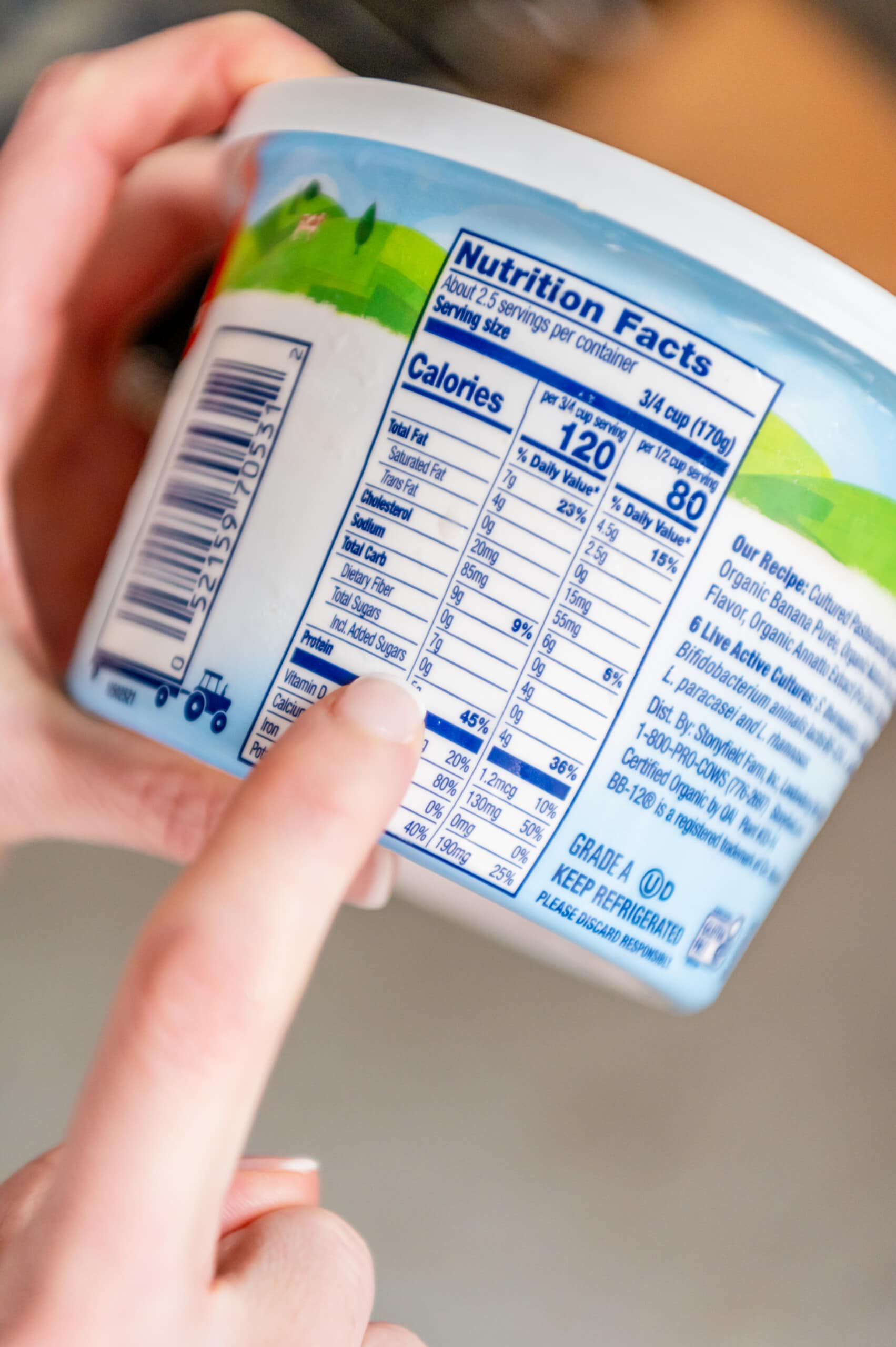 Finger pointing to nutrition facts and showing Stonyfield's new yobaby yogurt does not contain any added sugars